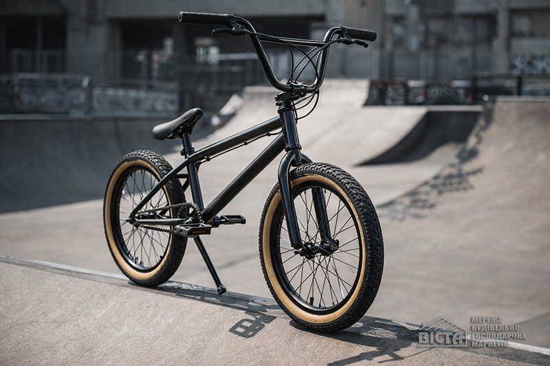 Велосипед типу BMX з посиленою рамою та маленькими колесами, розташований на бетонному покритті скейт-парку.